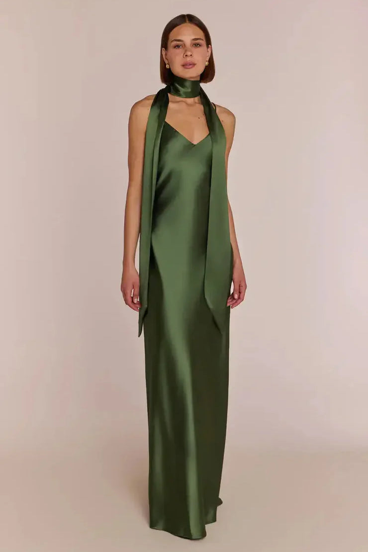 Woman wearing a green satin halter neck with REWRITTEN Brooklyn strappy-slip Bridesmaid Dress in Olive Green against a plain background