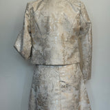 Back of an elegant women's two-piece jacquard outfit on a dress mannequin, featuring a light cream and silver floral-patterned 