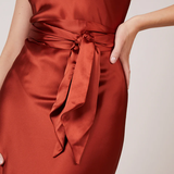 A studio photo of a flowy, rustic-colored satin dress.