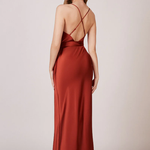 A studio photo of a brunette white woman wearing a flowy, rustic-colored satin dress.