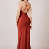 A studio photo of a brunette white woman wearing a flowy, rustic-colored satin dress.