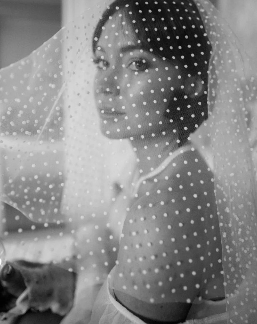 A woman wearing a white polka dot shoulder veil.