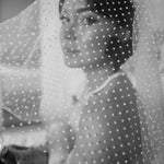 A woman wearing a white polka dot shoulder veil.