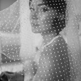 A woman wearing a white polka dot shoulder veil.