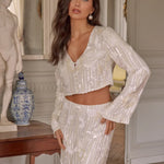 A brunette model wearing a sequin two-piece bridal cropped blouse and maxi skirt.