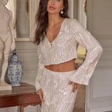 A brunette model wearing a sequin two-piece bridal cropped blouse and maxi skirt.
