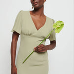 Woman in a  Chiffon Maxi bridesmaid dress holding a green flower against a white background