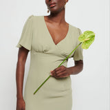 Woman in a  Chiffon Maxi bridesmaid dress holding a green flower against a white background