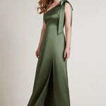 A studio photo of a brunette white woman wearing a body-hugging emerald green satin dress.