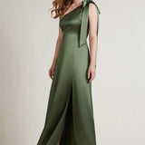 A studio photo of a brunette white woman wearing a body-hugging emerald green satin dress.