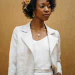 A woman wearing a white biker jacket with a floral lace design on the collar and a side front zip.