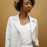 A woman wearing a white biker jacket with a floral lace design on the collar and a side front zip.