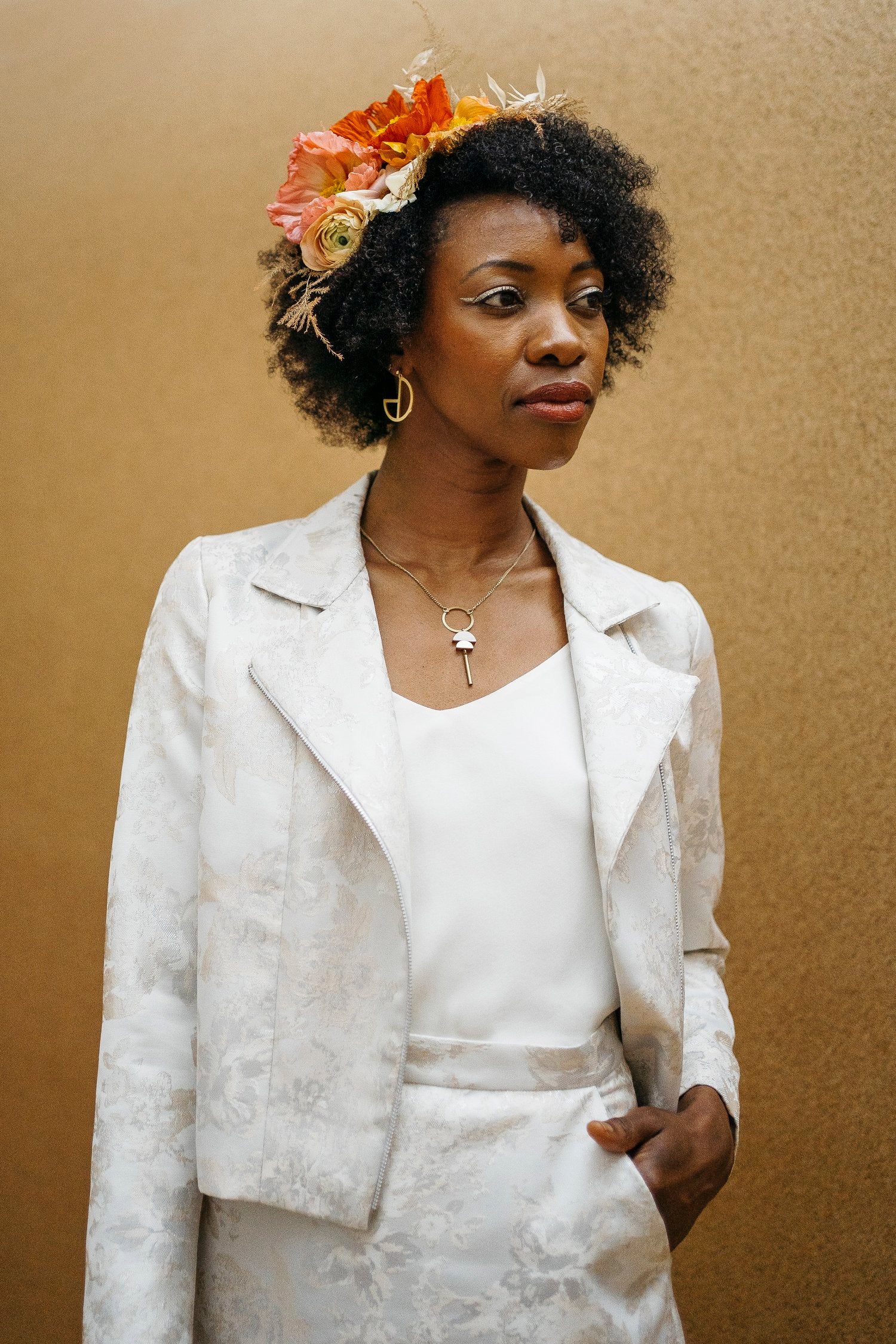 A woman wearing a white biker jacket with a floral lace design on the collar and a side front zip.