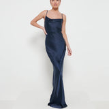 A woman wearing a navy maxi dress with a cowl neckline and spaghetti straps.