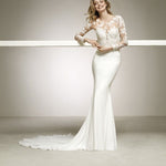 A white, v-neck, mermaid-cut wedding dress with lace inserts on the back and lower arms, featuring a skirt with a silver-screen style and a court train.