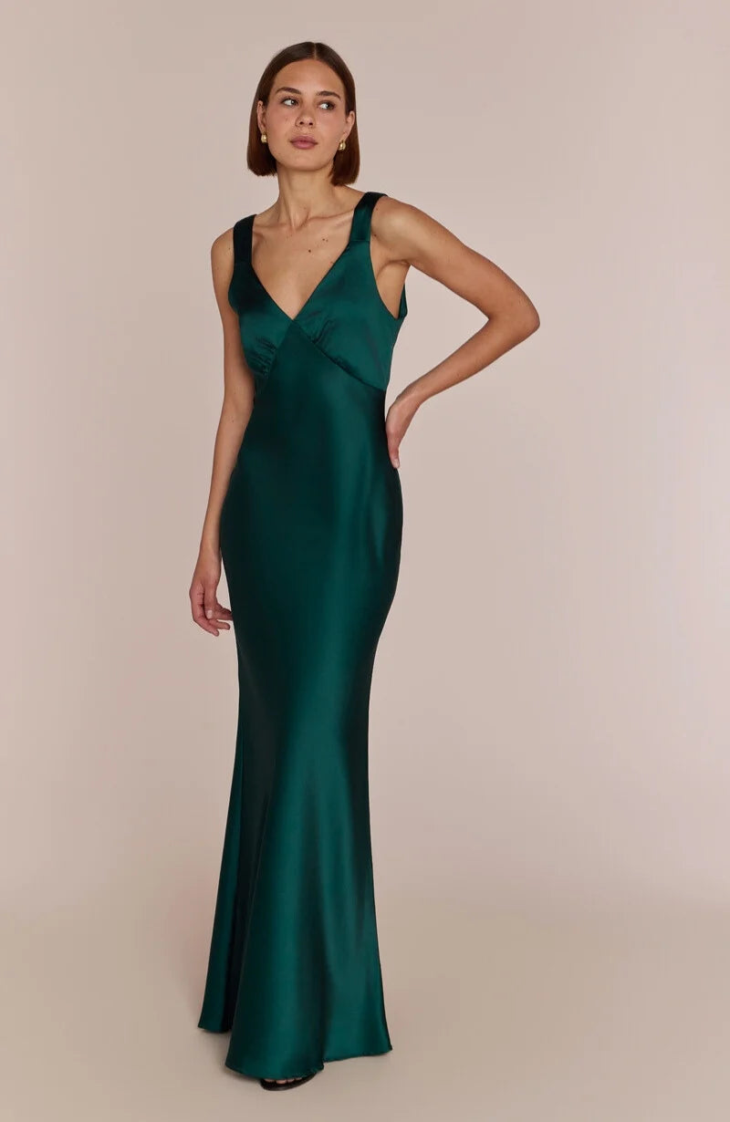 Woman wearing a green evening gown against a beige background