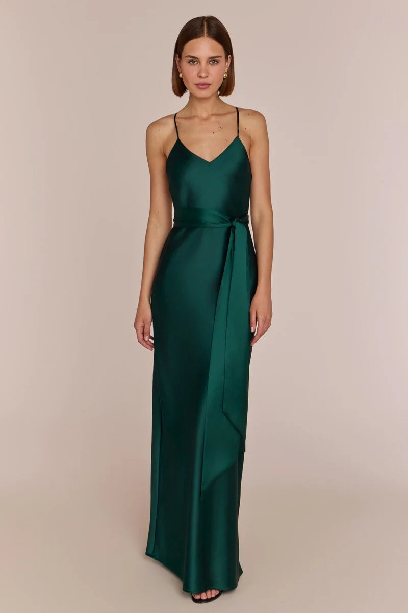Woman wearing a green satin gown against a beige background