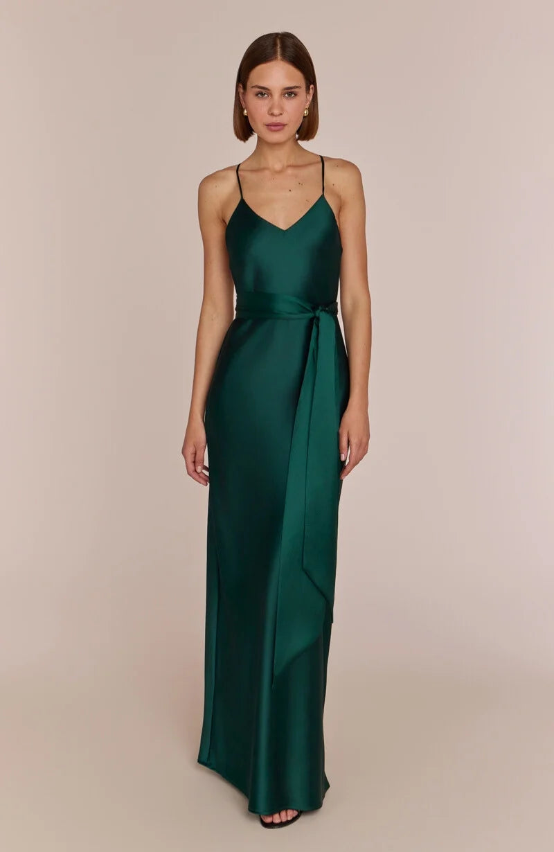 Woman wearing a green satin gown against a beige background