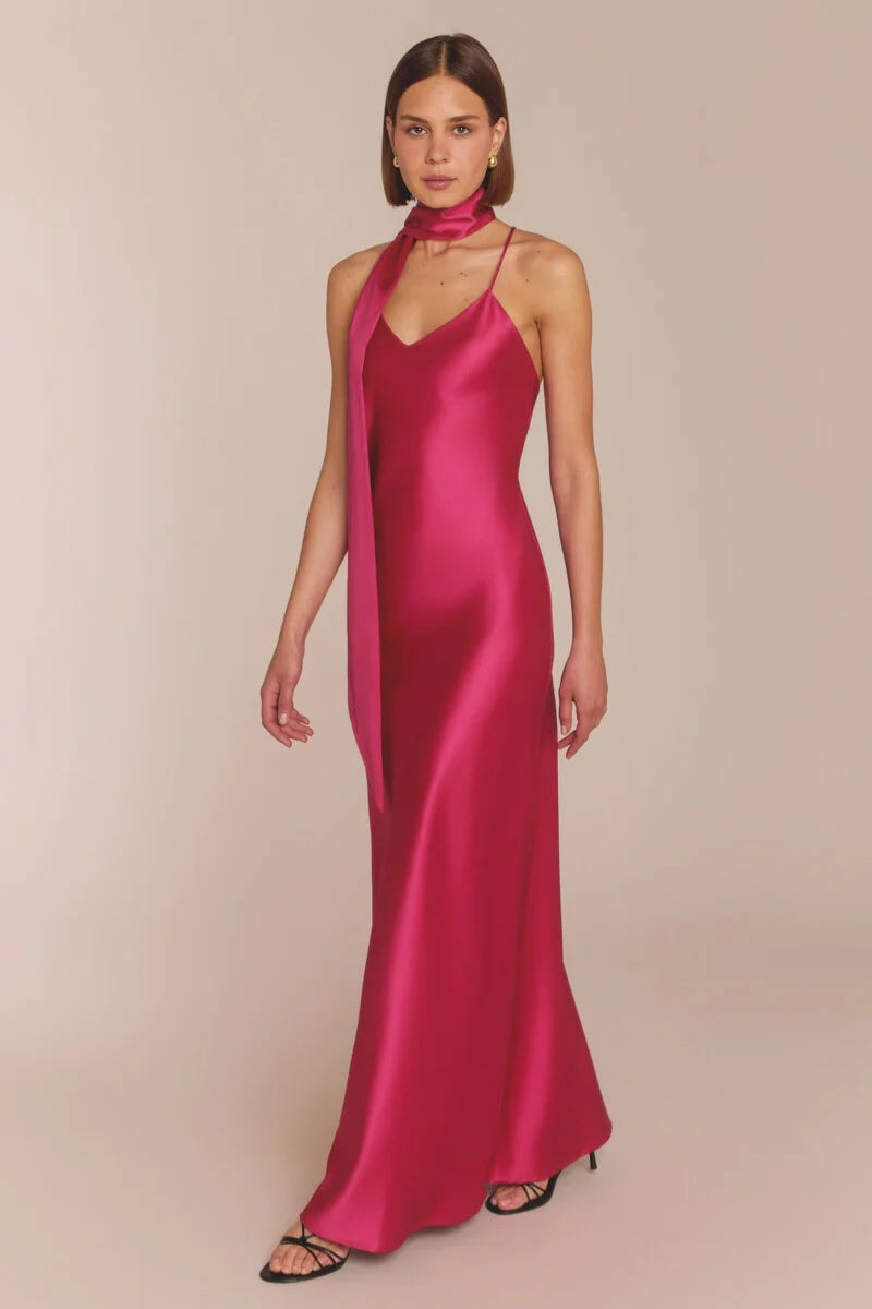 Woman wearing a pink satin gown with a plain background