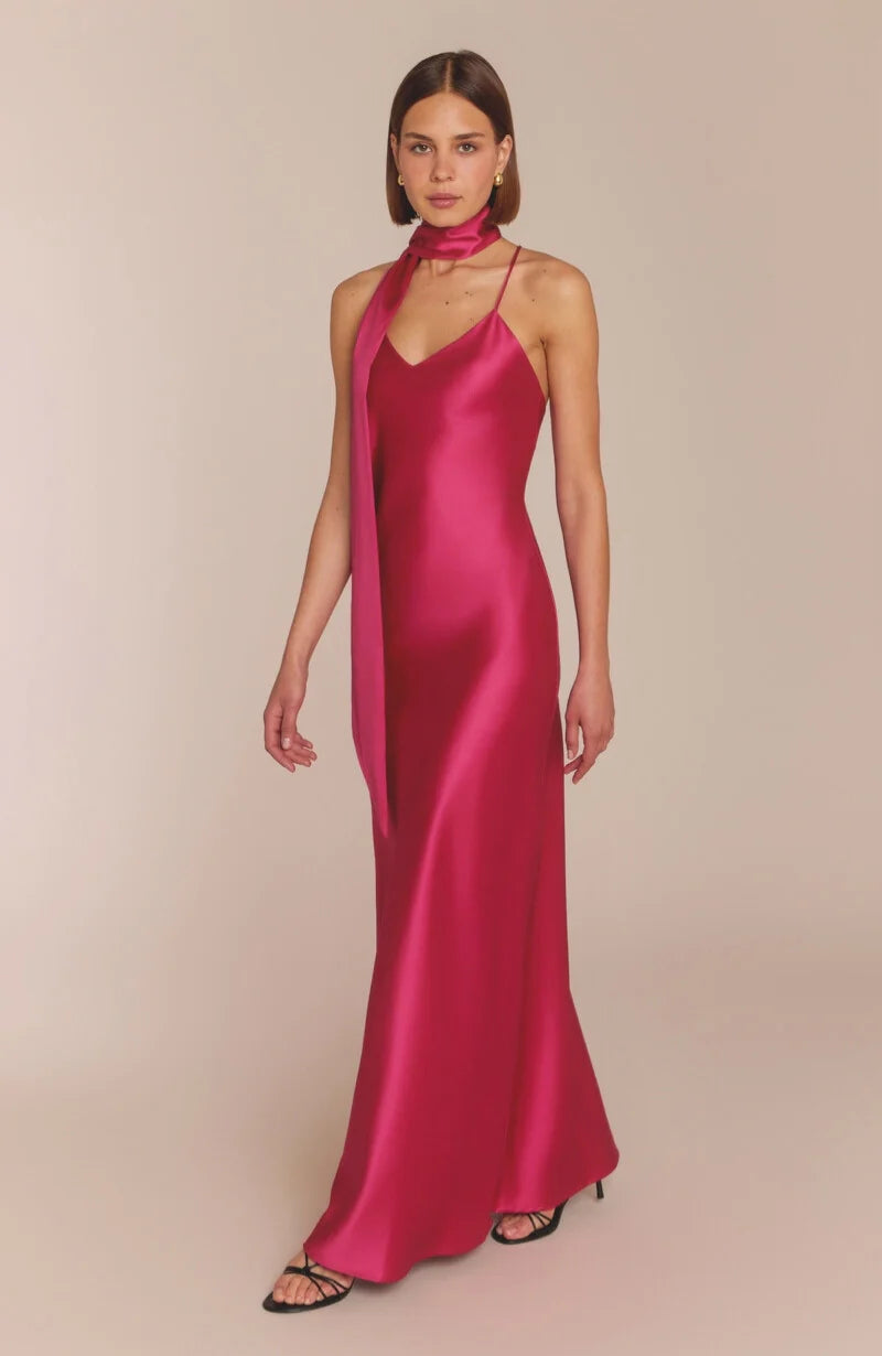 Woman wearing a pink satin gown with a plain background
