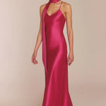 Woman wearing a pink satin gown with a plain background