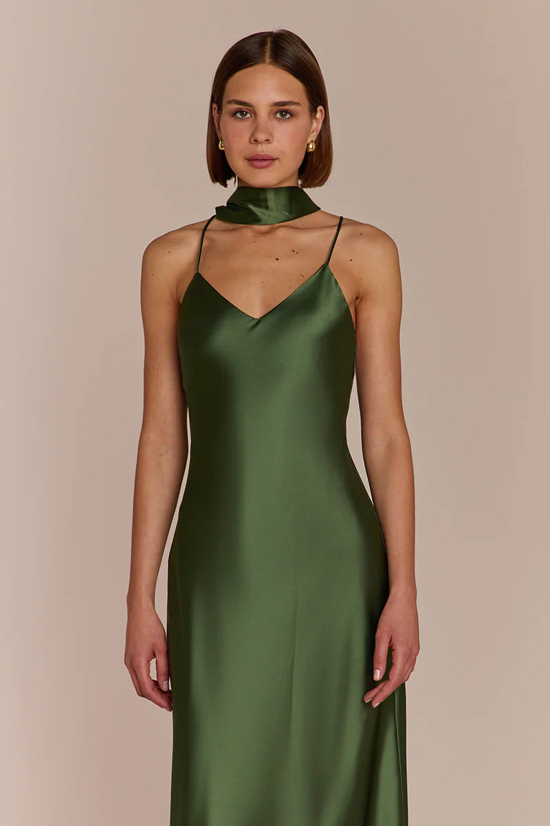 Woman wearing a green satin dress against a beige background