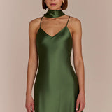 Woman wearing a green satin dress against a beige background