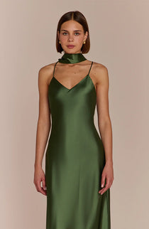 Woman wearing a green satin dress against a beige background