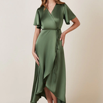 A woman standing and posing in an olive green, V-neck, short-sleeved, midi-length bridesmaid dress with a waterfall hem.