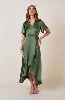A woman standing and posing in an olive green, V-neck, short-sleeved, midi-length bridesmaid dress with a waterfall hem.