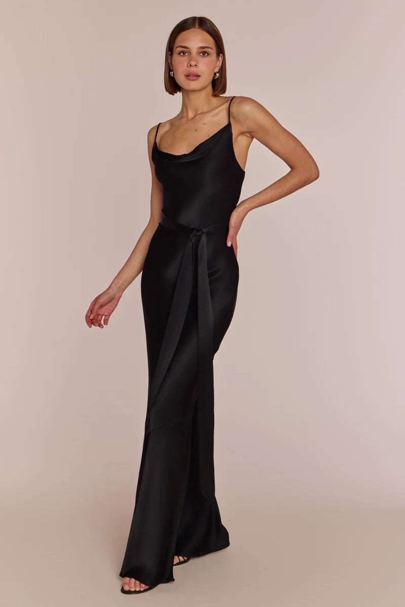 Woman wearing a black satin slip dress against a beige background