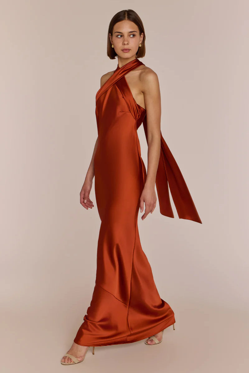 Woman wearing a rust-colored one-shoulder gown on a beige background