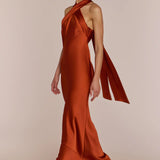 Woman wearing a rust-colored one-shoulder gown on a beige background