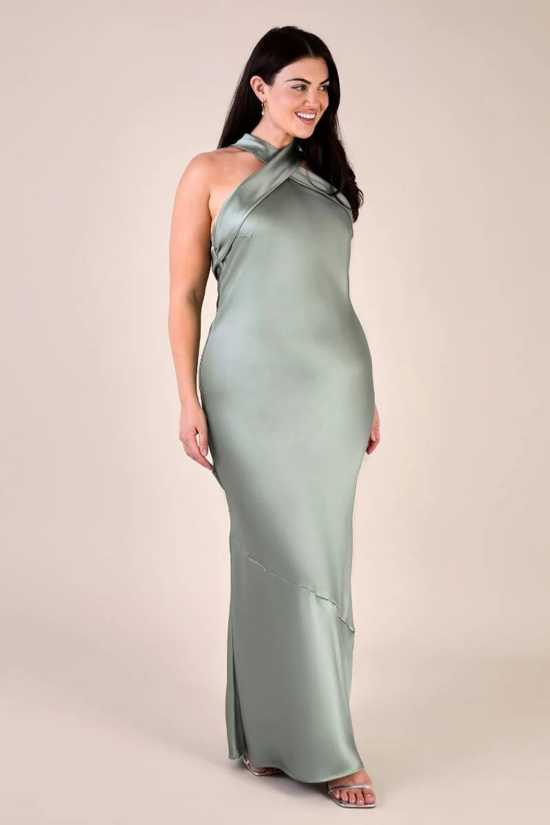Woman wearing a long green dress against a beige background