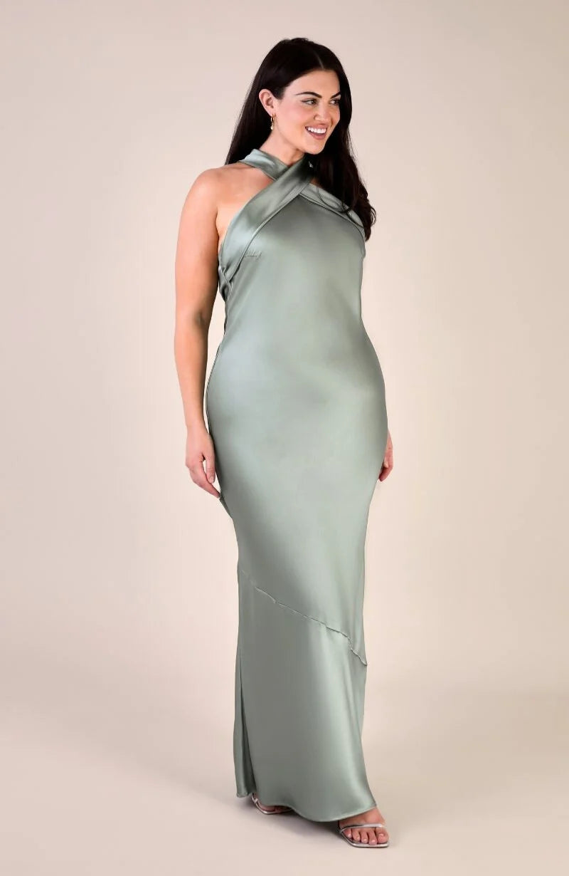Woman wearing a long green dress against a beige background