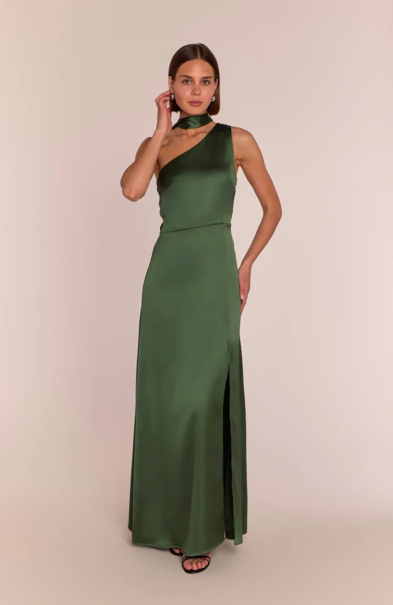 Woman wearing a green one-shoulder dress with a slit on a beige background