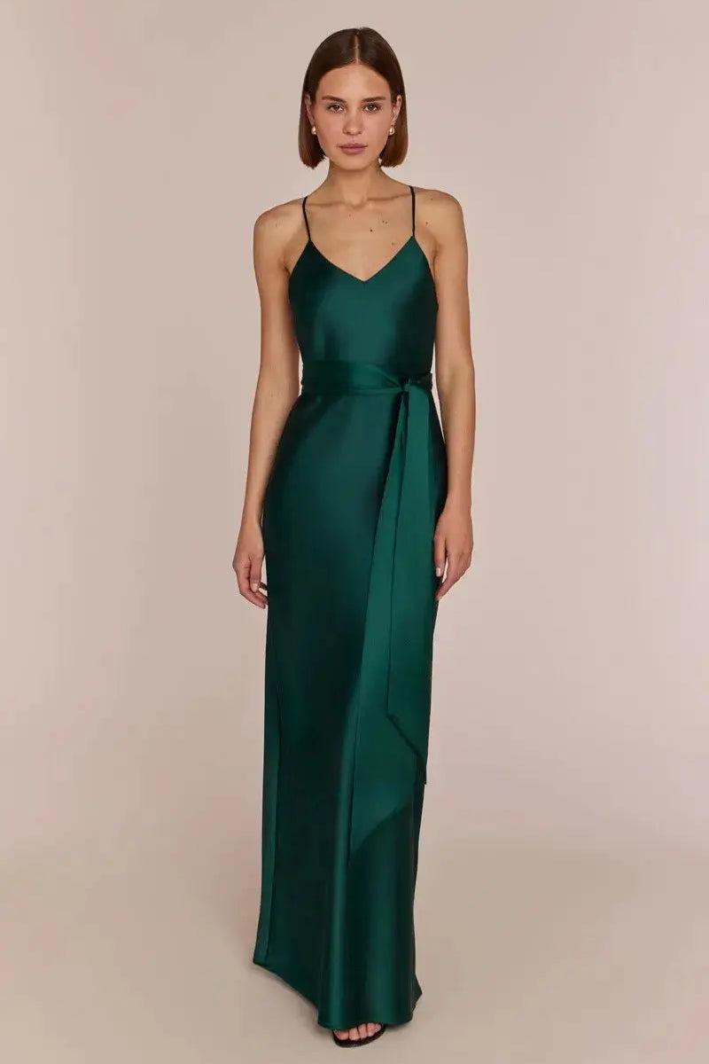 Woman wearing a Brooklyn strappy slip satin bridesmaids occasion-dress dark forest green against a beige background