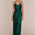 Woman wearing a Brooklyn strappy slip satin bridesmaids occasion-dress dark forest green against a beige background