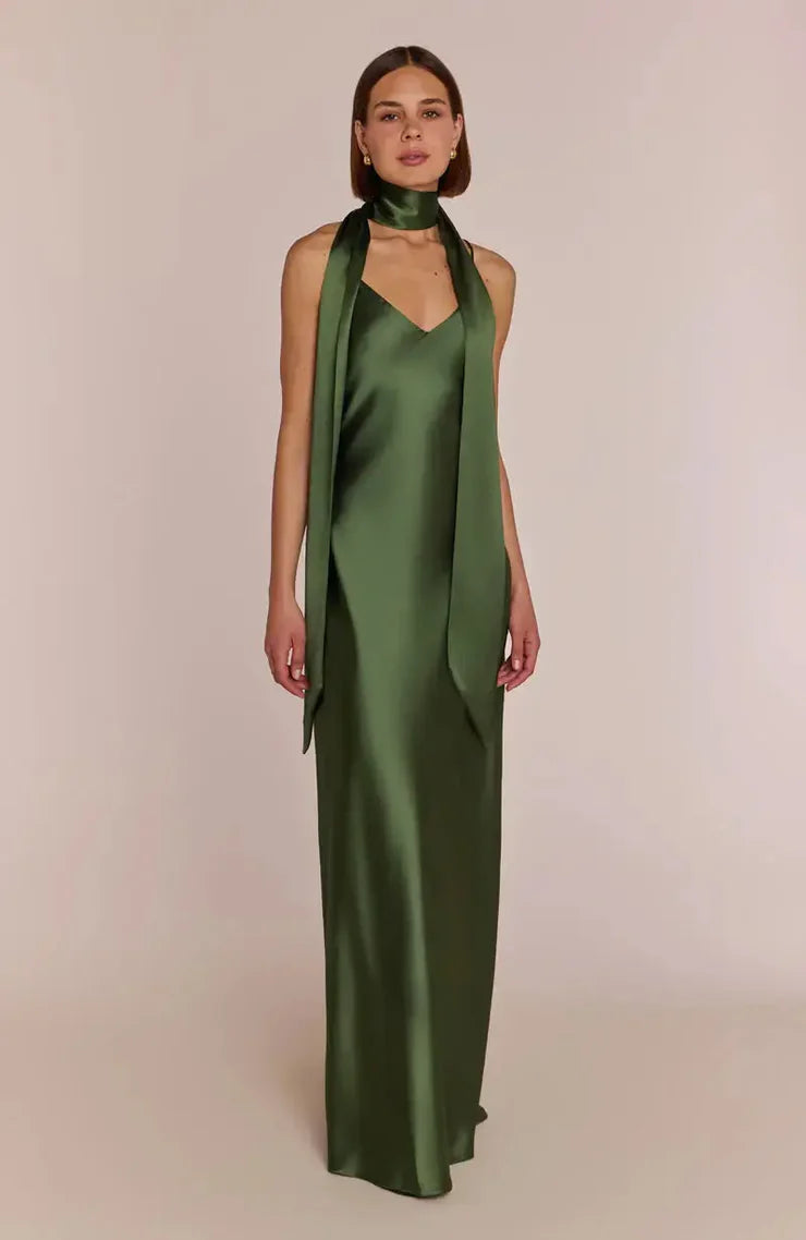 Woman wearing a green satin halter neck with REWRITTEN Brooklyn strappy-slip Bridesmaid Dress in Olive Green against a plain background